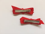 Two hair clips with bright red grosgrain bows